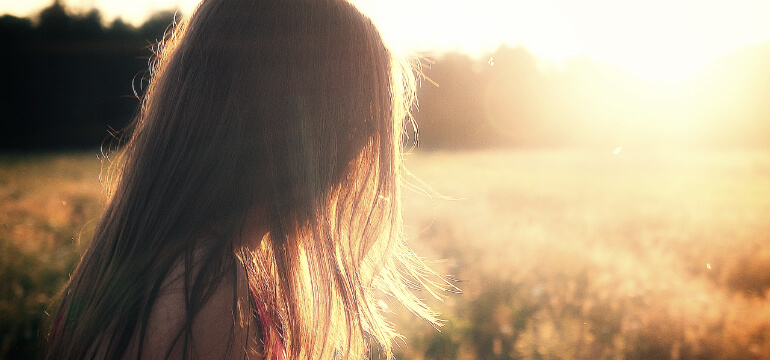 Profilen av en flicka med solen i ansiktet medan hon går runt på en åker
